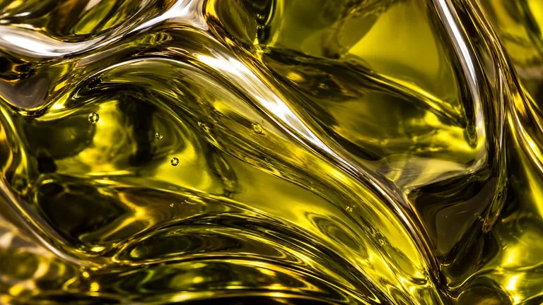 An immersive close-up of golden oil and Olune’s sculptural glass